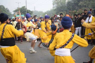 Delhi, Hindistan, 17 Kasım 2024 - Doğu Delhi bölgesinde Guru Nanak Dev, Nagar Kirtan 'ın doğum günü dolayısıyla geleneksel Nagar Kirtan, geleneksel Nagar geçit töreninde Sihler gatka ve dövüş sanatlarını sergiliyor