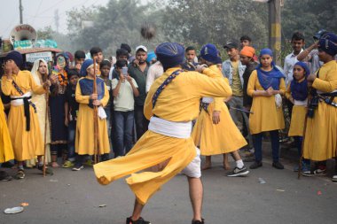 Delhi, Hindistan, 17 Kasım 2024 - Doğu Delhi bölgesinde Guru Nanak Dev, Nagar Kirtan 'ın doğum günü dolayısıyla geleneksel Nagar Kirtan, geleneksel Nagar geçit töreninde Sihler gatka ve dövüş sanatlarını sergiliyor