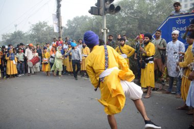 Delhi, Hindistan, 17 Kasım 2024 - Doğu Delhi bölgesinde Guru Nanak Dev, Nagar Kirtan 'ın doğum günü dolayısıyla geleneksel Nagar Kirtan, geleneksel Nagar geçit töreninde Sihler gatka ve dövüş sanatlarını sergiliyor