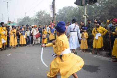 Delhi, Hindistan, 17 Kasım 2024 - Doğu Delhi bölgesinde Guru Nanak Dev, Nagar Kirtan 'ın doğum günü dolayısıyla geleneksel Nagar Kirtan, geleneksel Nagar geçit töreninde Sihler gatka ve dövüş sanatlarını sergiliyor