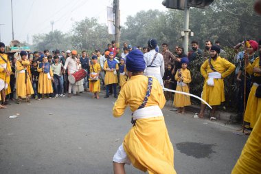 Delhi, Hindistan, 17 Kasım 2024 - Doğu Delhi bölgesinde Guru Nanak Dev, Nagar Kirtan 'ın doğum günü dolayısıyla geleneksel Nagar Kirtan, geleneksel Nagar geçit töreninde Sihler gatka ve dövüş sanatlarını sergiliyor