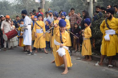Delhi, Hindistan, 17 Kasım 2024 - Doğu Delhi bölgesinde Guru Nanak Dev, Nagar Kirtan 'ın doğum günü dolayısıyla geleneksel Nagar Kirtan, geleneksel Nagar geçit töreninde Sihler gatka ve dövüş sanatlarını sergiliyor