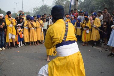 Delhi, Hindistan, 17 Kasım 2024 - Doğu Delhi bölgesinde Guru Nanak Dev, Nagar Kirtan 'ın doğum günü dolayısıyla geleneksel Nagar Kirtan, geleneksel Nagar geçit töreninde Sihler gatka ve dövüş sanatlarını sergiliyor