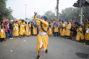 Delhi, Hindistan, 17 Kasım 2024 - Doğu Delhi bölgesinde Guru Nanak Dev, Nagar Kirtan 'ın doğum günü dolayısıyla geleneksel Nagar Kirtan, geleneksel Nagar geçit töreninde Sihler gatka ve dövüş sanatlarını sergiliyor