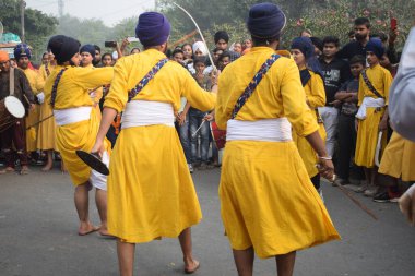 Delhi, Hindistan, 17 Kasım 2024 - Doğu Delhi bölgesinde Guru Nanak Dev, Nagar Kirtan 'ın doğum günü dolayısıyla geleneksel Nagar Kirtan, geleneksel Nagar geçit töreninde Sihler gatka ve dövüş sanatlarını sergiliyor