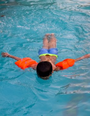 Havuzda yüzen mutlu Hintli çocuk, sıcak yaz tatillerinde hava tüpüyle birlikte yüzen çocuk, büyük bir havuzda yüzen çocuk..