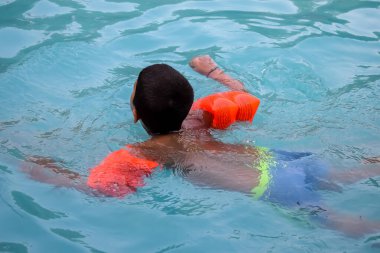 Havuzda yüzen mutlu Hintli çocuk, sıcak yaz tatillerinde hava tüpüyle birlikte yüzen çocuk, büyük bir havuzda yüzen çocuk..