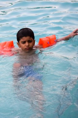 Havuzda yüzen mutlu Hintli çocuk, sıcak yaz tatillerinde hava tüpüyle birlikte yüzen çocuk, büyük bir havuzda yüzen çocuk..