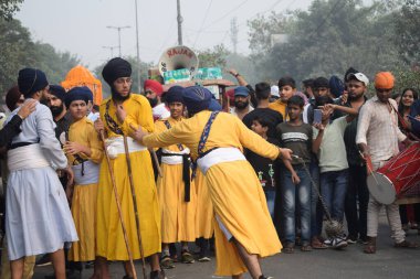Delhi, Hindistan, 17 Kasım 2024 - Doğu Delhi bölgesinde Guru Nanak Dev, Nagar Kirtan 'ın doğum günü dolayısıyla geleneksel Nagar Kirtan, geleneksel Nagar geçit töreninde Sihler gatka ve dövüş sanatlarını sergiliyor