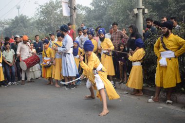 Delhi, Hindistan, 17 Kasım 2024 - Doğu Delhi bölgesinde Guru Nanak Dev, Nagar Kirtan 'ın doğum günü dolayısıyla geleneksel Nagar Kirtan, geleneksel Nagar geçit töreninde Sihler gatka ve dövüş sanatlarını sergiliyor