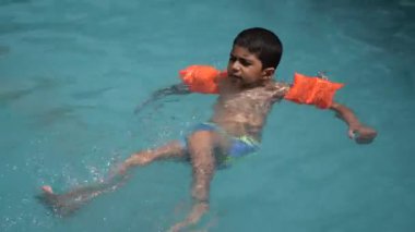 Havuzda yüzen mutlu Hintli çocuk, sıcak yaz tatillerinde hava tüpüyle birlikte yüzen çocuk, büyük bir havuzda yüzen çocuk..