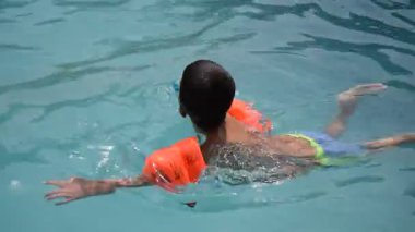 Havuzda yüzen mutlu Hintli çocuk, sıcak yaz tatillerinde hava tüpüyle birlikte yüzen çocuk, büyük bir havuzda yüzen çocuk..