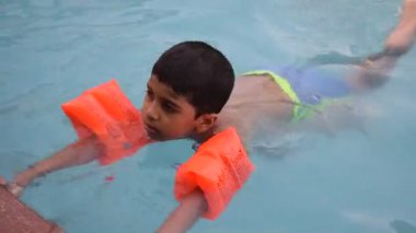 Havuzda yüzen mutlu Hintli çocuk, sıcak yaz tatillerinde hava tüpüyle birlikte yüzen çocuk, büyük bir havuzda yüzen çocuk..
