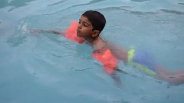 Havuzda yüzen mutlu Hintli çocuk, sıcak yaz tatillerinde hava tüpüyle birlikte yüzen çocuk, büyük bir havuzda yüzen çocuk..