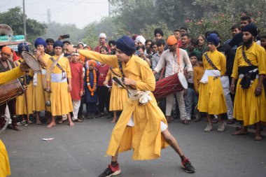 Delhi, Hindistan, 17 Kasım 2024 - Doğu Delhi bölgesinde Guru Nanak Dev, Nagar Kirtan 'ın doğum günü dolayısıyla geleneksel Nagar Kirtan, geleneksel Nagar geçit töreninde Sihler gatka ve dövüş sanatlarını sergiliyor