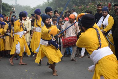 Delhi, Hindistan, 17 Kasım 2024 - Doğu Delhi bölgesinde Guru Nanak Dev, Nagar Kirtan 'ın doğum günü dolayısıyla geleneksel Nagar Kirtan, geleneksel Nagar geçit töreninde Sihler gatka ve dövüş sanatlarını sergiliyor