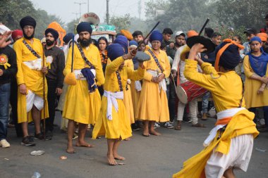 Delhi, Hindistan, 17 Kasım 2024 - Doğu Delhi bölgesinde Guru Nanak Dev, Nagar Kirtan 'ın doğum günü dolayısıyla geleneksel Nagar Kirtan, geleneksel Nagar geçit töreninde Sihler gatka ve dövüş sanatlarını sergiliyor
