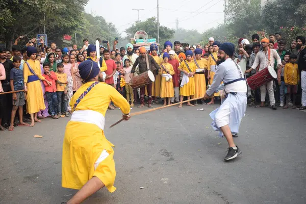 Delhi, Hindistan, 17 Kasım 2024 - Doğu Delhi bölgesinde Guru Nanak Dev, Nagar Kirtan 'ın doğum günü dolayısıyla geleneksel Nagar Kirtan, geleneksel Nagar geçit töreninde Sihler gatka ve dövüş sanatlarını sergiliyor