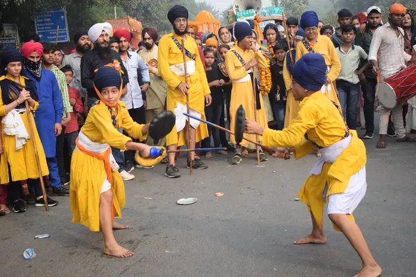 Delhi, Hindistan, 17 Kasım 2024 - Doğu Delhi bölgesinde Guru Nanak Dev, Nagar Kirtan 'ın doğum günü dolayısıyla geleneksel Nagar Kirtan, geleneksel Nagar geçit töreninde Sihler gatka ve dövüş sanatlarını sergiliyor
