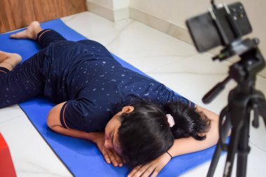 Evde yoga yapan genç Hintli bir kadın çevrimiçi yoga seansında güzel bir kız temel yoga pozisyonunda Asyalı bir kadın kapalı alanda yoga yapıyor.