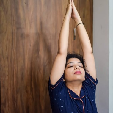 Evde yoga yapan genç Hintli bir kadın çevrimiçi yoga seansında güzel bir kız temel yoga pozisyonunda Asyalı bir kadın kapalı alanda yoga yapıyor.