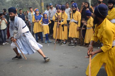 Delhi, Hindistan, 17 Kasım 2024 - Doğu Delhi bölgesinde Guru Nanak Dev, Nagar Kirtan 'ın doğum günü dolayısıyla geleneksel Nagar Kirtan, geleneksel Nagar geçit töreninde Sihler gatka ve dövüş sanatlarını sergiliyor