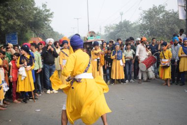 Delhi, Hindistan, 17 Kasım 2024 - Doğu Delhi bölgesinde Guru Nanak Dev, Nagar Kirtan 'ın doğum günü dolayısıyla geleneksel Nagar Kirtan, geleneksel Nagar geçit töreninde Sihler gatka ve dövüş sanatlarını sergiliyor