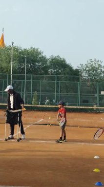 Delhi, Hindistan, 17 Şubat 2025 - Maha Open için kil tenis kortunda antrenörlük yapan genç tenisçiler, yaklaşan turnuva için küçük tenis oyuncuları antrenman yapıyor