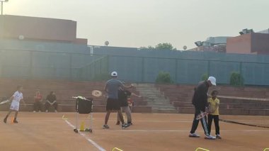 Delhi, Hindistan, 17 Şubat 2025 - Maha Open için kil tenis kortunda antrenörlük yapan genç tenisçiler, yaklaşan turnuva için küçük tenis oyuncuları antrenman yapıyor