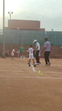 Delhi, Hindistan, 17 Şubat 2025 - Maha Open için kil tenis kortunda antrenörlük yapan genç tenisçiler, yaklaşan turnuva için küçük tenis oyuncuları antrenman yapıyor