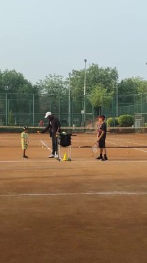 Delhi, Hindistan, 17 Şubat 2025 - Maha Open için kil tenis kortunda antrenörlük yapan genç tenisçiler, yaklaşan turnuva için küçük tenis oyuncuları antrenman yapıyor