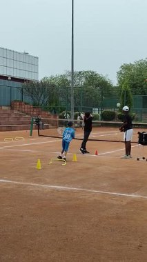 Delhi, Hindistan, 17 Şubat 2025 - Maha Open için kil tenis kortunda antrenörlük yapan genç tenisçiler, yaklaşan turnuva için küçük tenis oyuncuları antrenman yapıyor