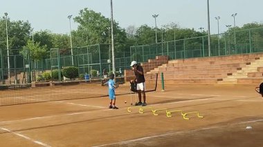 Delhi, Hindistan, 17 Şubat 2025 - Maha Open için kil tenis kortunda antrenörlük yapan genç tenisçiler, yaklaşan turnuva için küçük tenis oyuncuları antrenman yapıyor