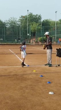 Delhi, Hindistan, 17 Şubat 2025 - Maha Open için kil tenis kortunda antrenörlük yapan genç tenisçiler, yaklaşan turnuva için küçük tenis oyuncuları antrenman yapıyor