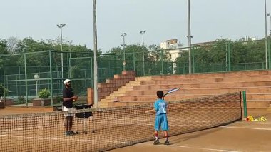 Delhi, Hindistan, 17 Şubat 2025 - Maha Open için kil tenis kortunda antrenörlük yapan genç tenisçiler, yaklaşan turnuva için küçük tenis oyuncuları antrenman yapıyor