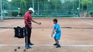 Delhi, Hindistan, 17 Şubat 2025 - Maha Open için kil tenis kortunda antrenörlük yapan genç tenisçiler, yaklaşan turnuva için küçük tenis oyuncuları antrenman yapıyor