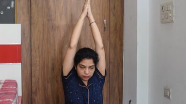 Evde yoga yapan genç Hintli bir kadın çevrimiçi yoga seansında güzel bir kız temel yoga pozisyonunda Asyalı bir kadın kapalı alanda yoga yapıyor. 