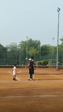 Delhi, Hindistan, 17 Şubat 2025 - Maha Open için kil tenis kortunda antrenörlük yapan genç tenisçiler, yaklaşan turnuva için küçük tenis oyuncuları antrenman yapıyor
