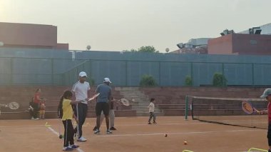 Delhi, Hindistan, 17 Şubat 2025 - Maha Open için kil tenis kortunda antrenörlük yapan genç tenisçiler, yaklaşan turnuva için küçük tenis oyuncuları antrenman yapıyor