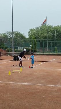 Delhi, Hindistan, 17 Şubat 2025 - Maha Open için kil tenis kortunda antrenörlük yapan genç tenisçiler, yaklaşan turnuva için küçük tenis oyuncuları antrenman yapıyor