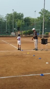 Delhi, Hindistan, 17 Şubat 2025 - Maha Open için kil tenis kortunda antrenörlük yapan genç tenisçiler, yaklaşan turnuva için küçük tenis oyuncuları antrenman yapıyor