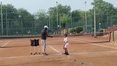 Delhi, Hindistan, 17 Şubat 2025 - Maha Open için kil tenis kortunda antrenörlük yapan genç tenisçiler, yaklaşan turnuva için küçük tenis oyuncuları antrenman yapıyor