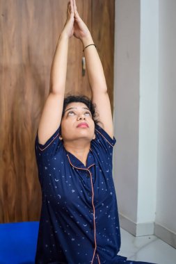 Evde yoga yapan genç Hintli bir kadın çevrimiçi yoga seansında güzel bir kız temel yoga pozisyonunda Asyalı bir kadın kapalı alanda yoga yapıyor.