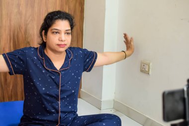 Evde yoga yapan genç Hintli bir kadın çevrimiçi yoga seansında güzel bir kız temel yoga pozisyonunda Asyalı bir kadın kapalı alanda yoga yapıyor.