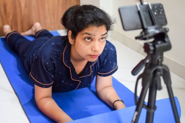 Evde yoga yapan genç Hintli bir kadın çevrimiçi yoga seansında güzel bir kız temel yoga pozisyonunda Asyalı bir kadın kapalı alanda yoga yapıyor.