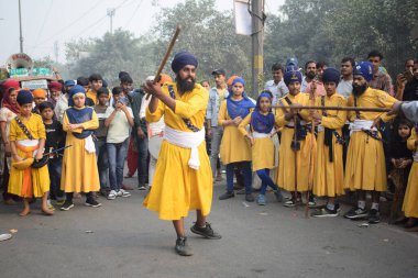 Delhi, Hindistan, 17 Kasım 2024 - Doğu Delhi bölgesinde Guru Nanak Dev, Nagar Kirtan 'ın doğum günü dolayısıyla geleneksel Nagar Kirtan, geleneksel Nagar geçit töreninde Sihler gatka ve dövüş sanatlarını sergiliyor