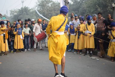 Delhi, Hindistan, 17 Kasım 2024 - Doğu Delhi bölgesinde Guru Nanak Dev, Nagar Kirtan 'ın doğum günü dolayısıyla geleneksel Nagar Kirtan, geleneksel Nagar geçit töreninde Sihler gatka ve dövüş sanatlarını sergiliyor
