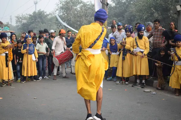 Delhi, Hindistan, 17 Kasım 2024 - Doğu Delhi bölgesinde Guru Nanak Dev, Nagar Kirtan 'ın doğum günü dolayısıyla geleneksel Nagar Kirtan, geleneksel Nagar geçit töreninde Sihler gatka ve dövüş sanatlarını sergiliyor
