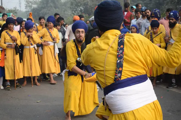 Delhi, Hindistan, 17 Kasım 2024 - Doğu Delhi bölgesinde Guru Nanak Dev, Nagar Kirtan 'ın doğum günü dolayısıyla geleneksel Nagar Kirtan, geleneksel Nagar geçit töreninde Sihler gatka ve dövüş sanatlarını sergiliyor
