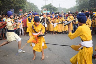 Delhi, Hindistan, 17 Kasım 2024 - Doğu Delhi bölgesinde Guru Nanak Dev, Nagar Kirtan 'ın doğum günü dolayısıyla geleneksel Nagar Kirtan, geleneksel Nagar geçit töreninde Sihler gatka ve dövüş sanatlarını sergiliyor